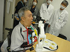 食事介助ロボットが金子氏の口元に食べ物を運んでいます